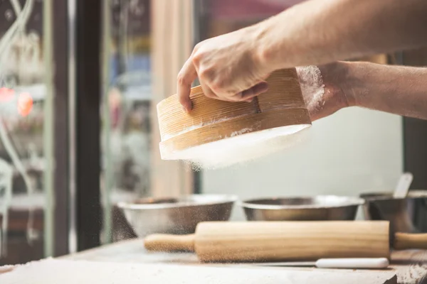 Man hands spilling powder on dough — Stock Photo, Image