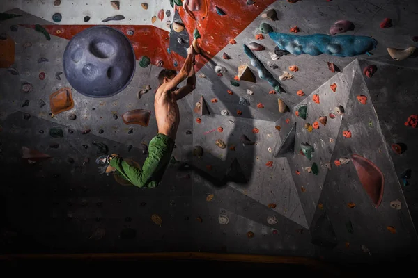 Homem praticando rock-escalada em uma parede de rocha dentro de casa — Fotografia de Stock