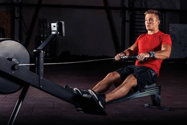spor salonunda kürek makine kullanan genç adam