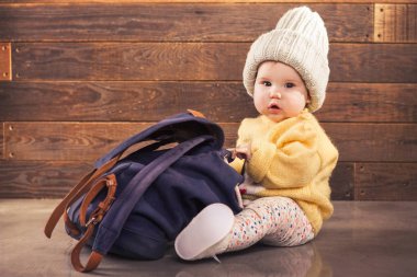 Ahşap arka plan üzerinde sırt çantası ile şirin bebek