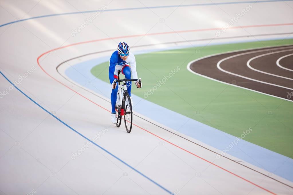 Racing cyclist on velodrome outdoor.