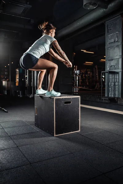 Fille sportive sautant par-dessus certaines boîtes dans la salle de gym — Photo