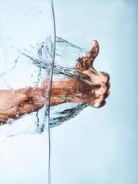 Puño de mujer a través del agua azul y gotas salpicaduras — Foto de Stock