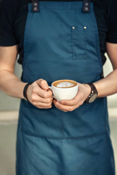 Barista sosteniendo una taza de café con arte latte — Foto de Stock