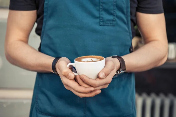 Barista sosteniendo una taza de café con arte latte — Foto de Stock