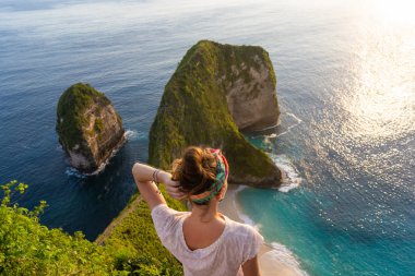 Uçurumun kenarında duran ve günbatımının tadını çıkaran kadın