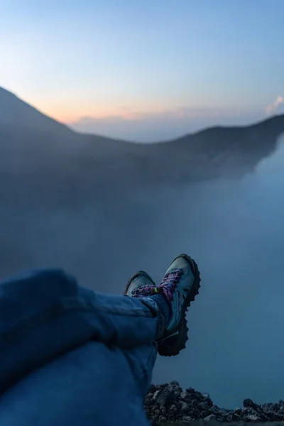 Adventure seeker sitting on the cliff and enjoying the view of a — Stock Photo, Image