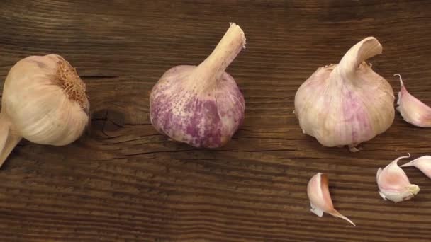 Groep van enkele knoflookteentjes en een klomp van knoflook op houten achtergrond — Stockvideo