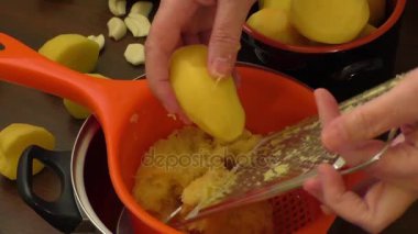 Rende ile kadınlar el üzerinde patatesleri rendeleyin mutfaktaki patates gözlemesi için