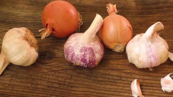 Knoflook bollen en UI op een houten bord, natuurgeneeskunde, eet gezond voedsel — Stockvideo