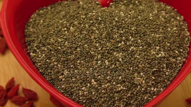 Semillas de chía en cuenco de cerámica en forma de corazón y bayas secas — Vídeo de stock