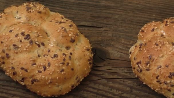 Pães de centeio frescos com sementes de gergelim em um fundo de madeira — Vídeo de Stock