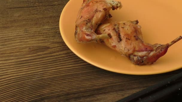 Patas de conejo al horno en un plato sobre un fondo de madera oscura — Vídeo de stock