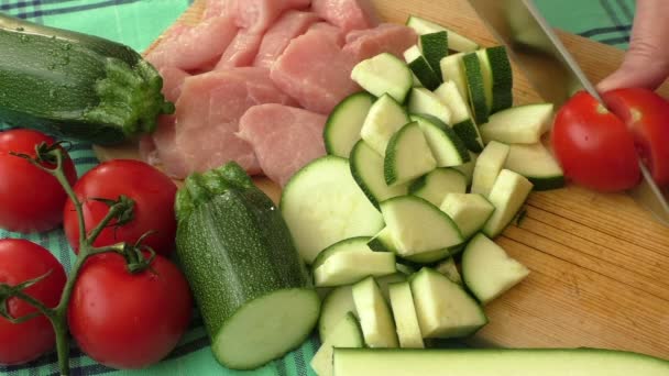 La carne fresca de cerdo en la tabla de cortar se corta en trozos con verduras — Vídeo de stock