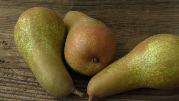 Three ripe juicy pears on a dark wooden table — Stock Video