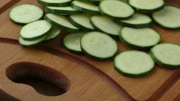 Zucchine fresche tagliate a fette sul tagliere, su fondo di legno — Video Stock