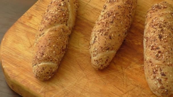 Whole-grain bread rolls on wooden cutting board — Stock Video