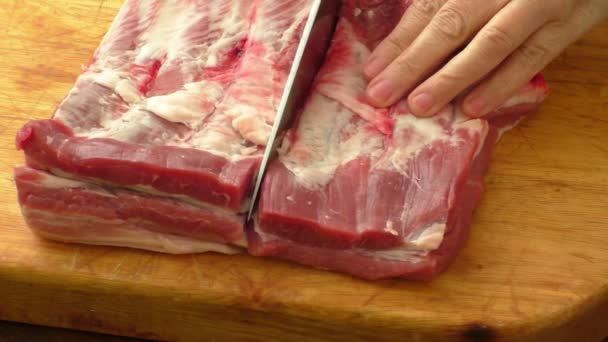 Мясо на борту и на руках. Нож режет сырую свинину — стоковое видео