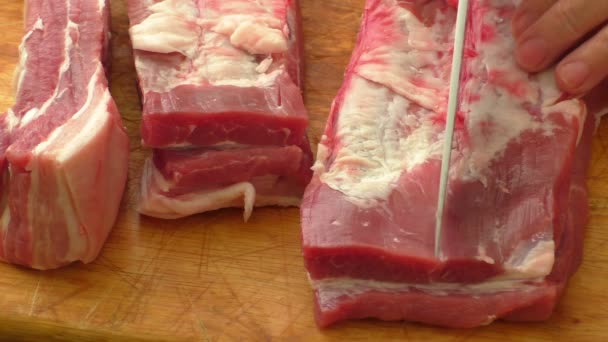 Vlees op bord en handen. Mes snijden rauw varkensvlees — Stockvideo