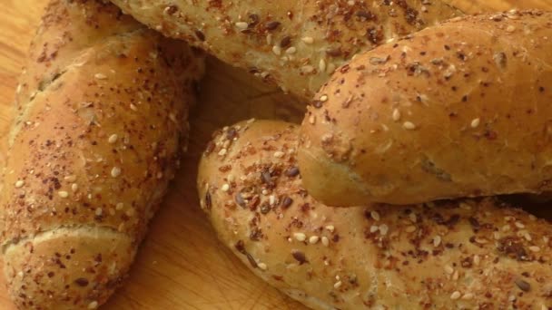 Freshly baked delicious crusty rolls on a rustic wooden worktop — Stock Video