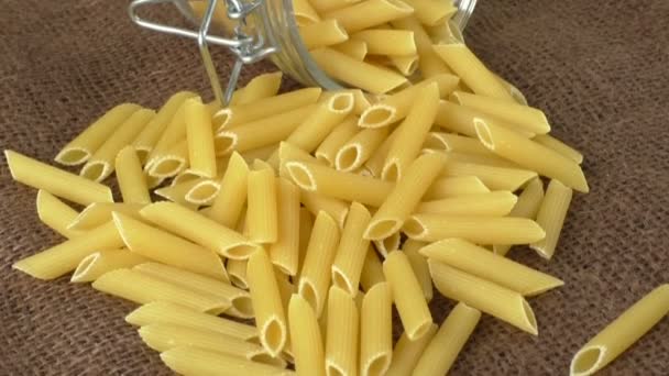Italiaanse pasta in glazen pot geïsoleerd op bruine achtergrond — Stockvideo
