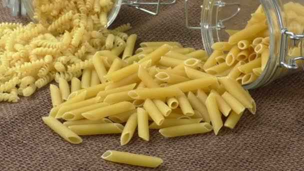 Italiaanse pasta in glazen pot geïsoleerd op bruine achtergrond — Stockvideo