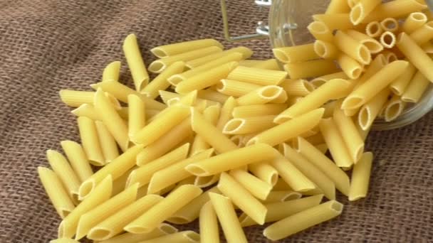 Skleněný džbán plněné těstoviny suché rotini žluté izolované hnědé pozadí — Stock video