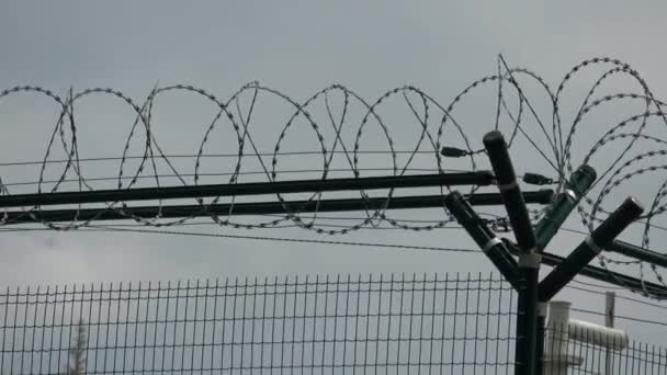 灰色の空と有刺鉄線でセキュリティ フェンス。有刺鉄線のフェンス. — ストック動画