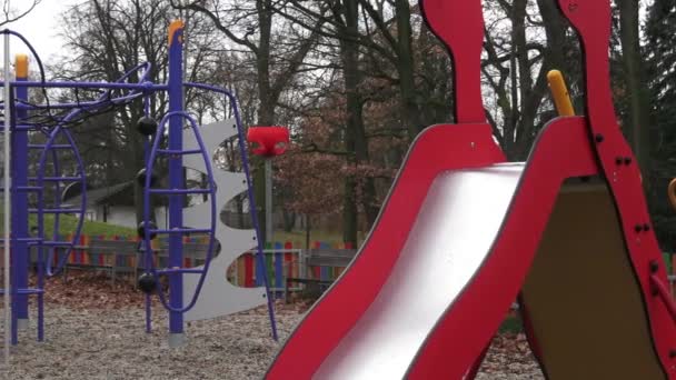 Разноцветные детские игровые площадки в общественном парке в окружении деревьев . — стоковое видео