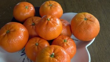 Mandalinalar masanın üzerinde bir tabakta yatıyor. 