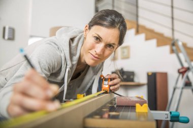 Single young woman standing by workbench at home clipart