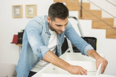 Genç adam evde mobilya parçaları montaj