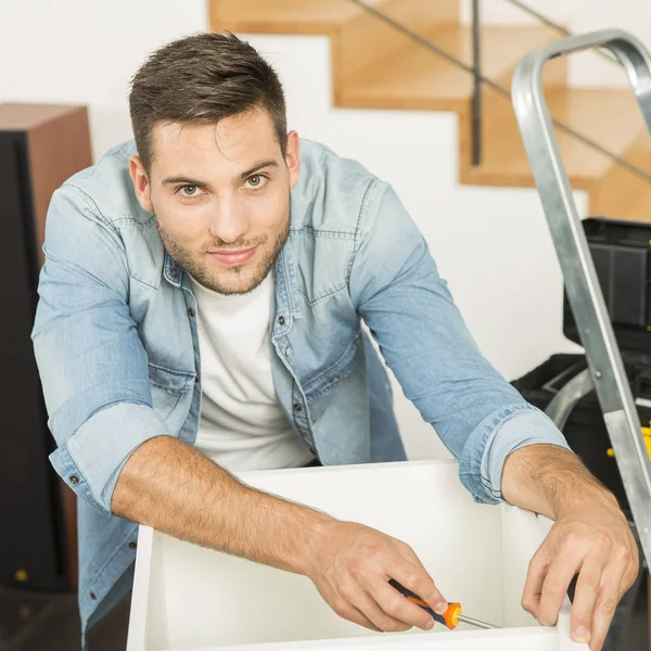 Young man at home assembling furniture parts — Stock Photo, Image