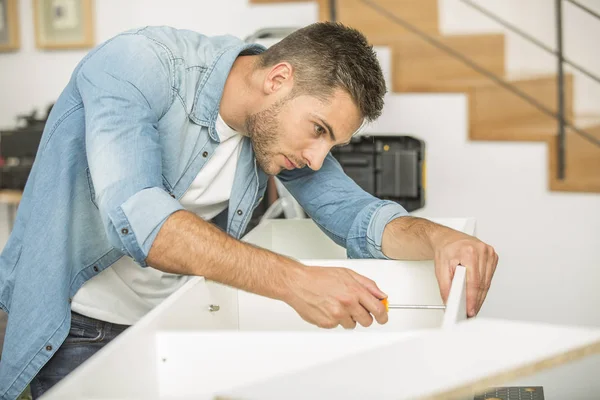 Jovem em casa montando peças de mobiliário — Fotografia de Stock