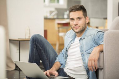 genç adamın evde dizüstü bilgisayar kullanarak üst görünüm