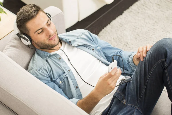 Cheerful man relaxing in sofa, listening to music — Stock Photo, Image