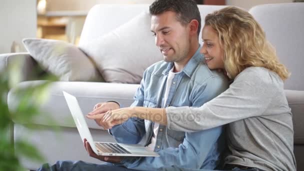 Feliz pareja joven viendo internet en su computadora portátil — Vídeo de stock
