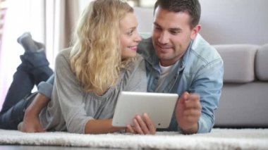 Mutlu genç çift halının üzerine koydu onların oturma odası ve bir tablet kullanma