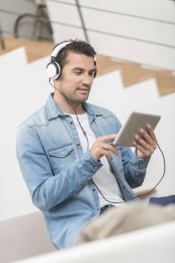 yakışıklı genç duyuyor müzik wwith bir tablet portresi bir