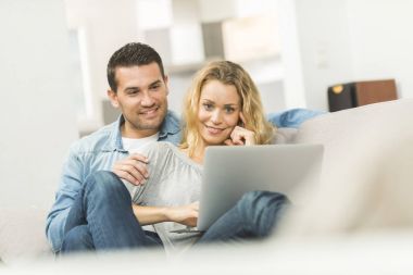 Onların dizüstü bilgisayarda İnternet izlerken mutlu genç Çift
