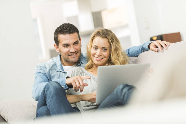 Счастливая молодая пара смотрит интернет на своем ноутбуке
