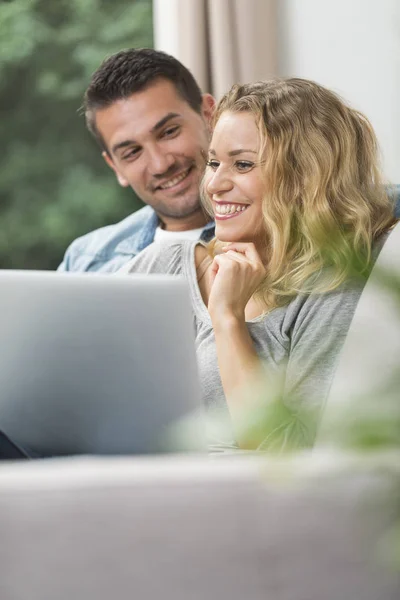 Feliz jovem casal assistindo internet em seu laptop — Fotografia de Stock