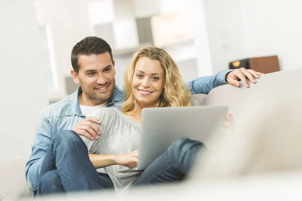 Feliz jovem casal assistindo internet em seu laptop — Fotografia de Stock