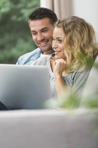 Gelukkige jonge paar internetverbinding in de gaten op hun laptop — Stockfoto