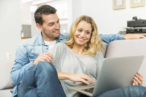Casal jovem aproveitando ao máximo as novas tecnologias em sua casa — Fotografia de Stock