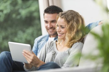 Mutlu genç çift tabletlerinde internet izliyor.