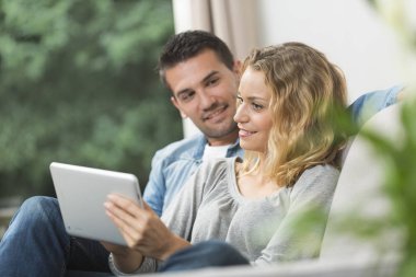 Mutlu genç çift tabletlerinde internet izliyor.