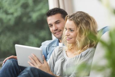 Mutlu genç çift tabletlerinde internet izliyor.