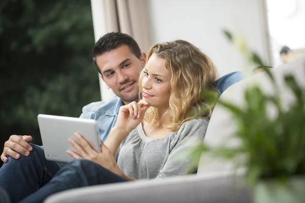 Feliz jovem casal assistindo internet em seu tablet — Fotografia de Stock