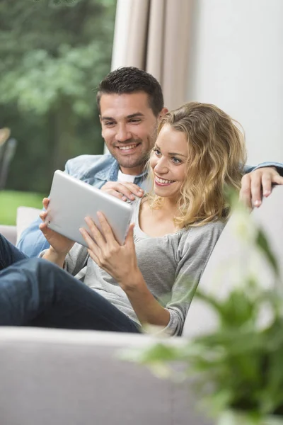 Happy young couple watching internet on their tablet — Stock Photo, Image